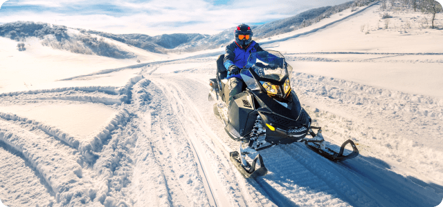 A person riding a snowmobile alone in an open area