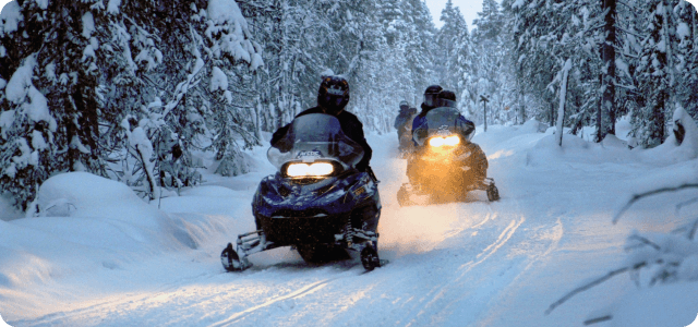 People riding snowmobiles at night with their headlights on