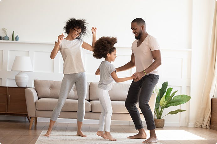 a man and woman and a child dancing near a couch