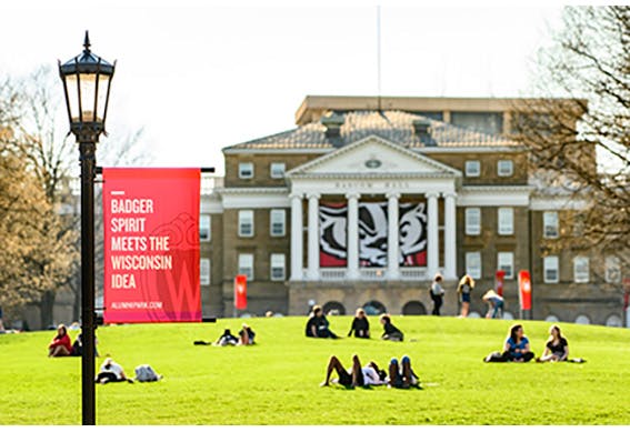 a group of people sitting on the grass in front of University of Wisconsin-Madison