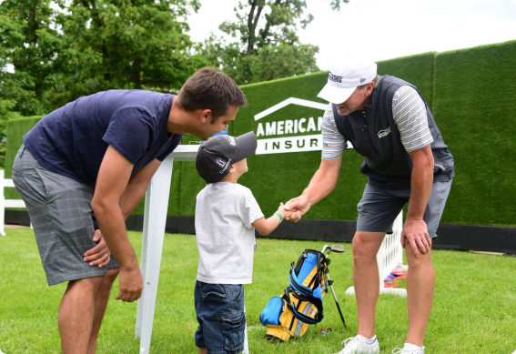 a golfer shaking hands with a young boy and his father
