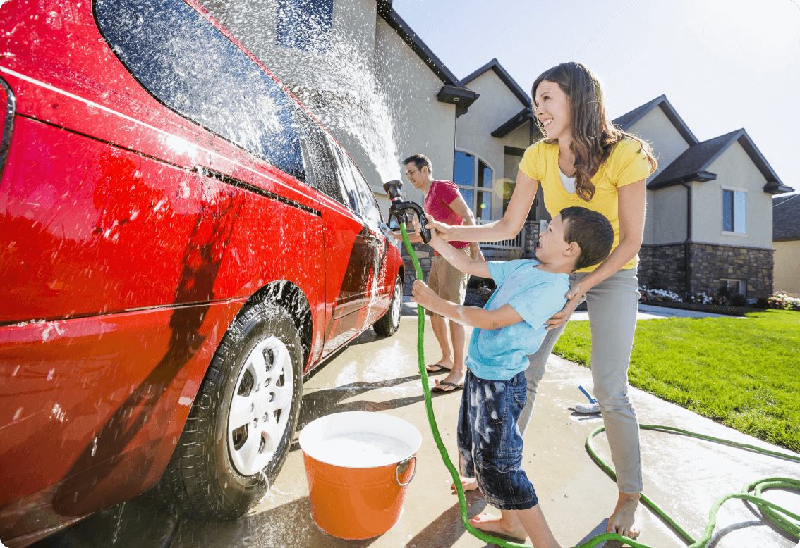 A family washing a car in the driveway