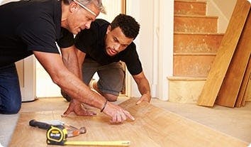 a couple of men working on a wood floor