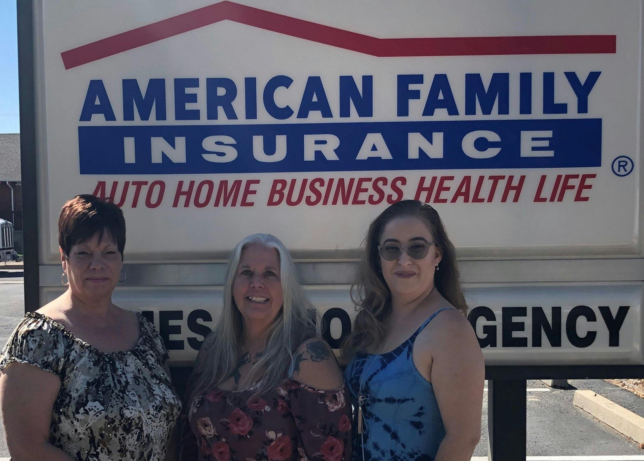a group of women posing for a photo in front of a sign
