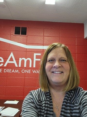 a woman smiling in front of a red wall