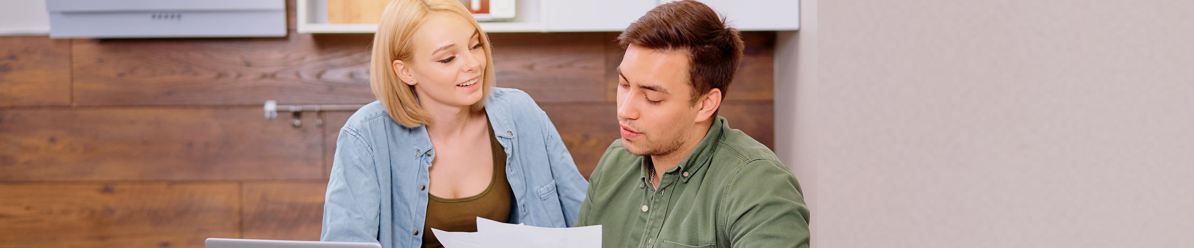 Image of a couple looking over their financial records as they contemplate refinancing their home.