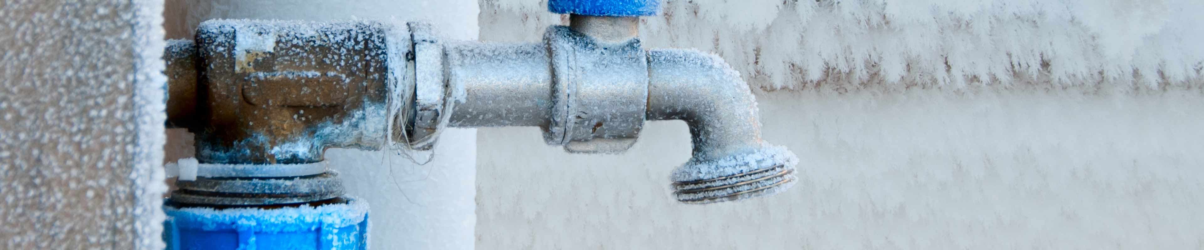 A frozen faucet outside of a home, connected to a pipe that may burst.
