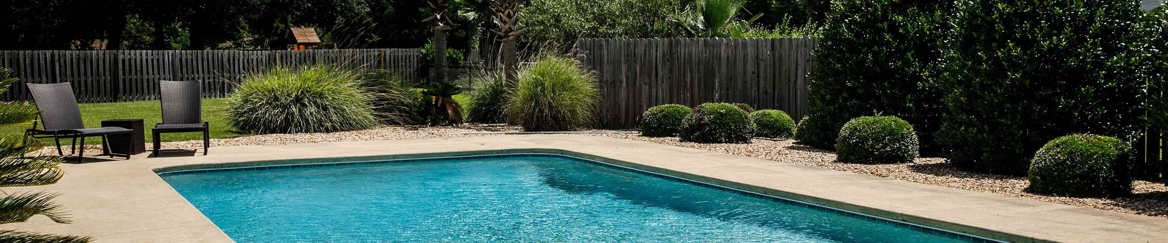 Swimming pool in a backyard with a fence.