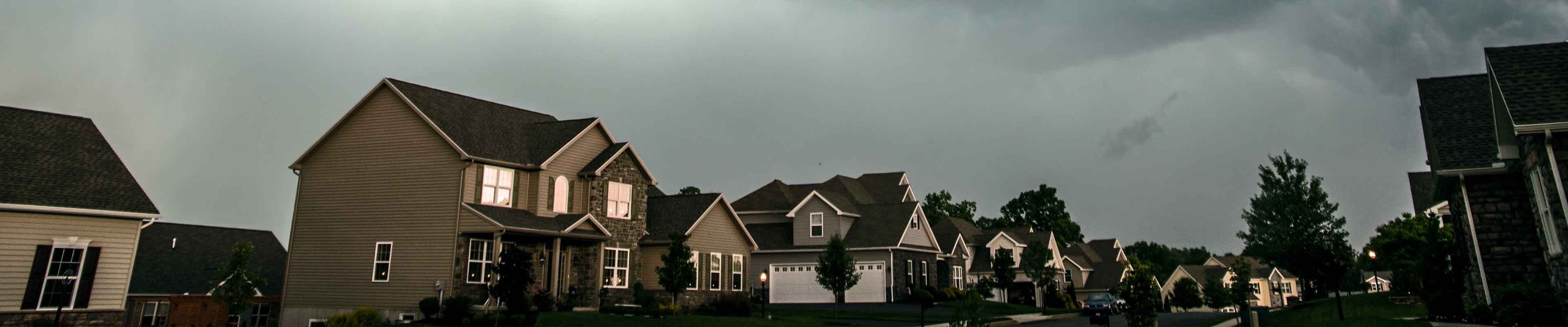 A storm with potential hail, winds and lightning looms over houses.