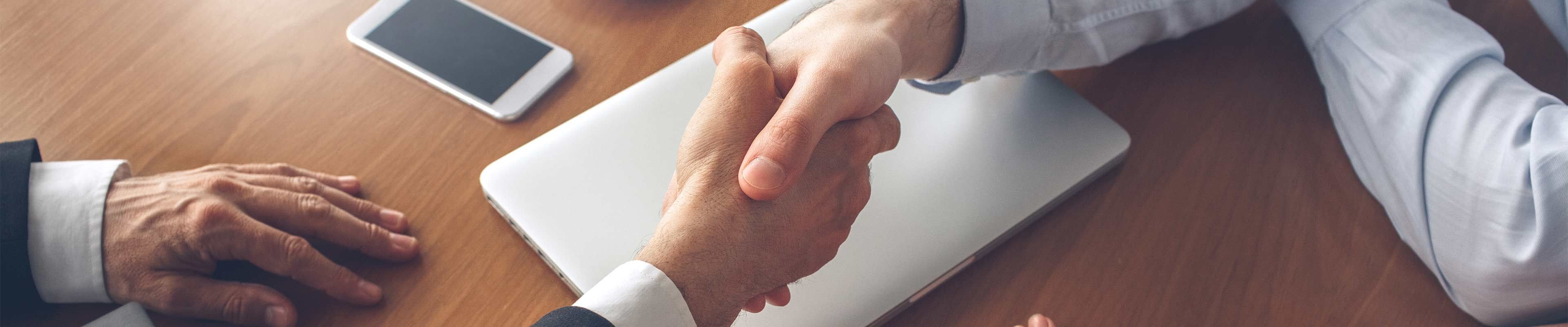 Two men shake hands after selling a home