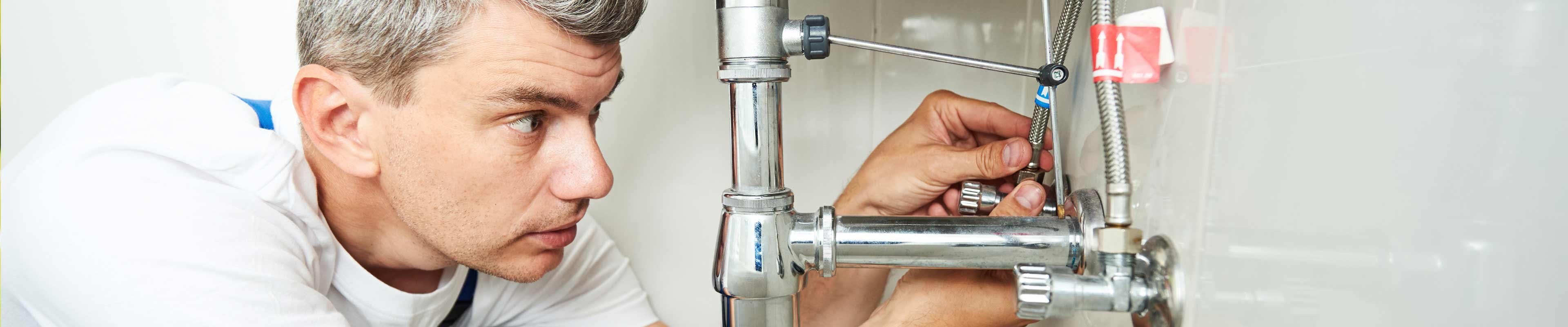 Image of a homeowner making repairs to plumbing under the sink.