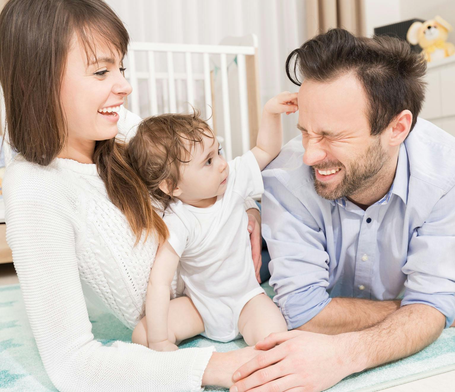 mother and father laughing with young baby