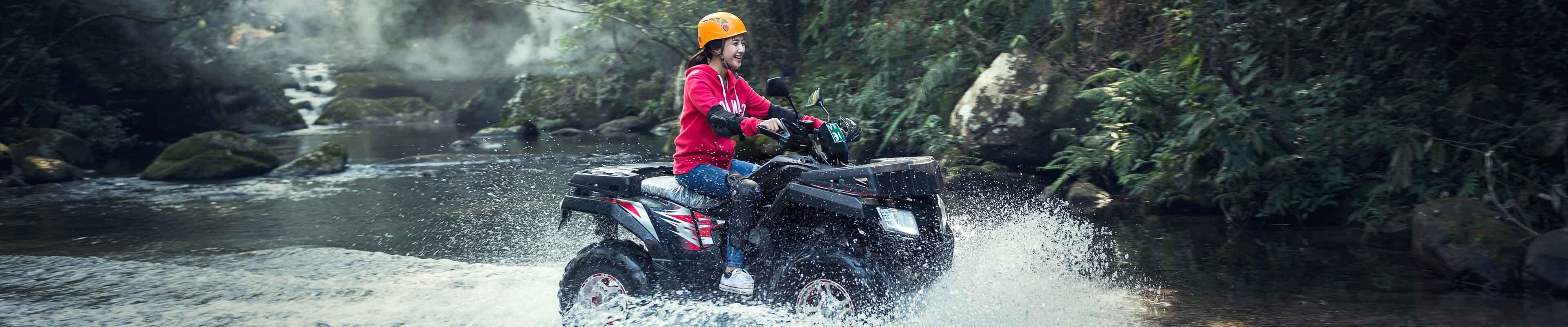 Girl riding through river on ATV.