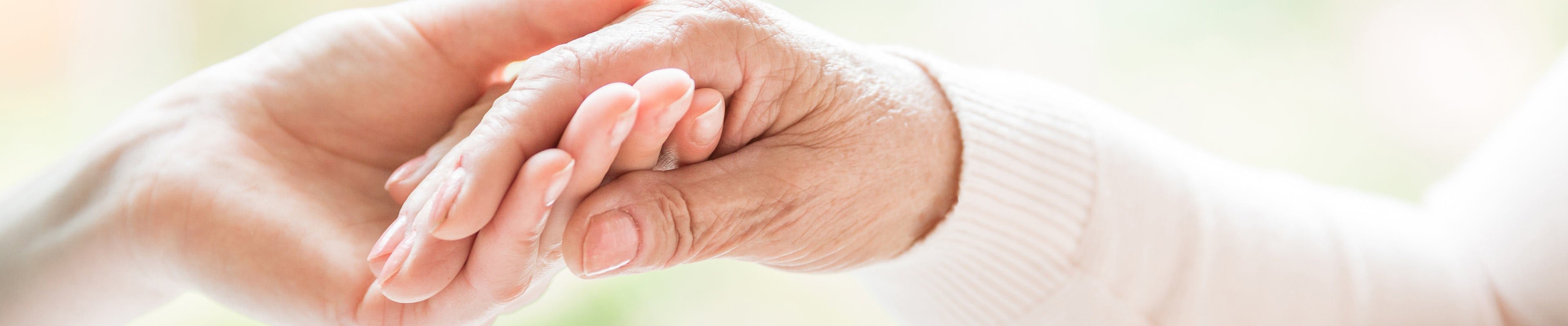 Respite caregiver holding hands of elderly patient