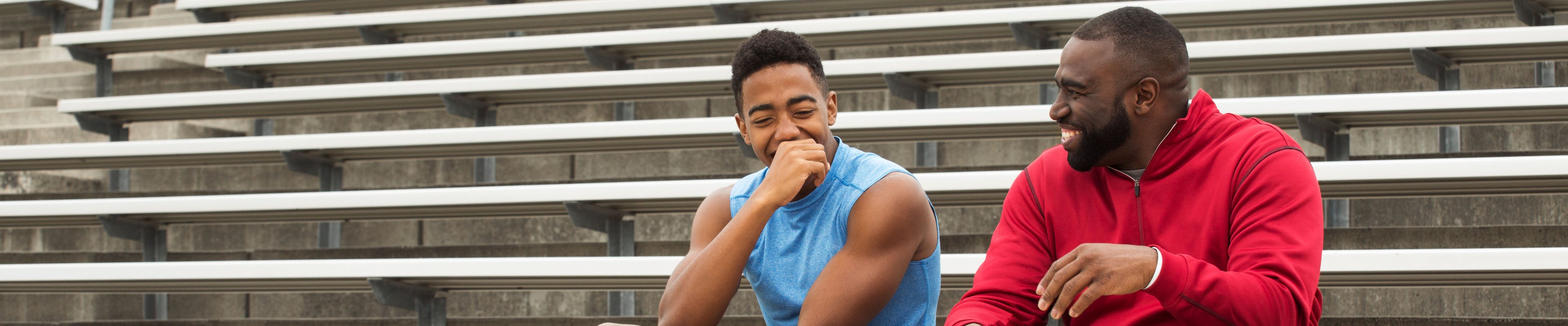 An adult man sitting with young male on the bleachers