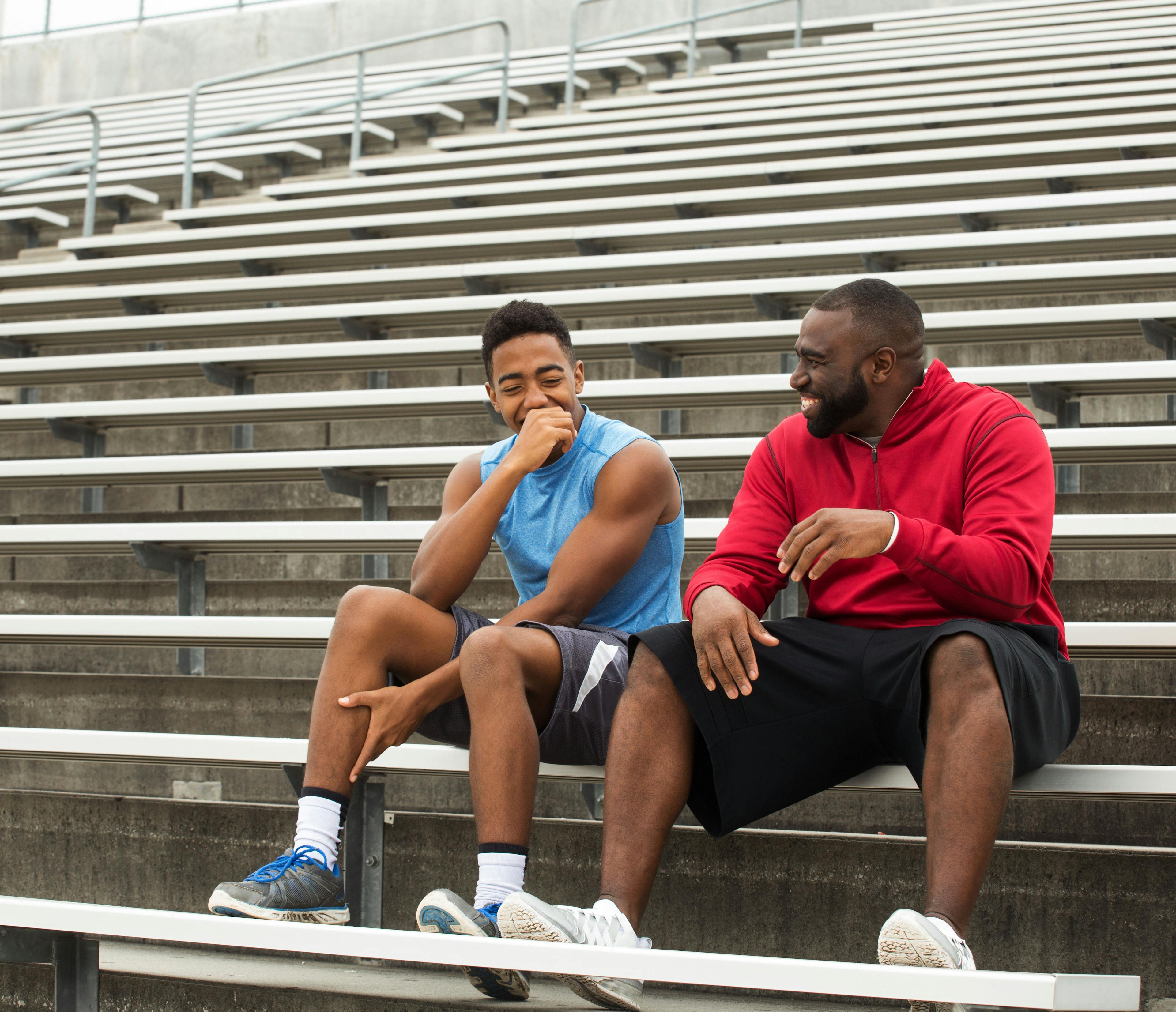 An adult man sitting with young male on the bleachers