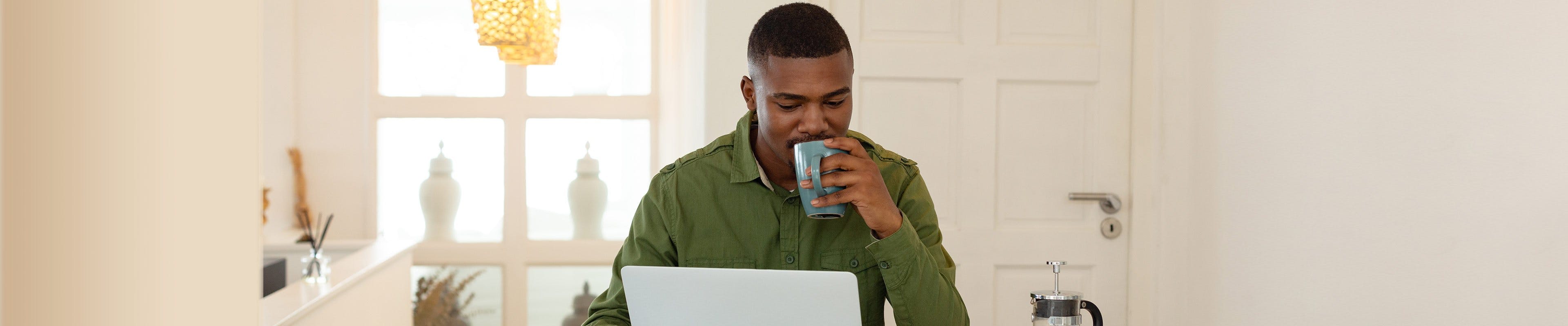 Image of a man browsing the internet and drinking coffee, looking at ways to save on groceries.