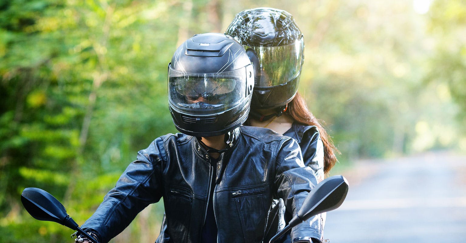 Couple riding a motorcycle while wearing helmets