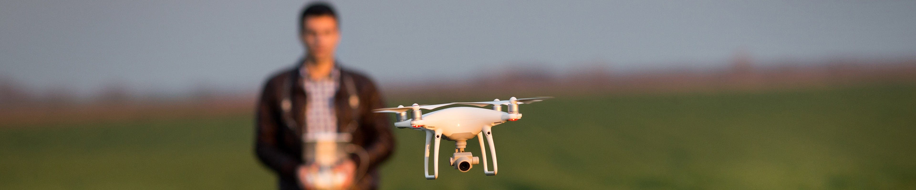 Image of a farmer operating a drone over a soybean field.