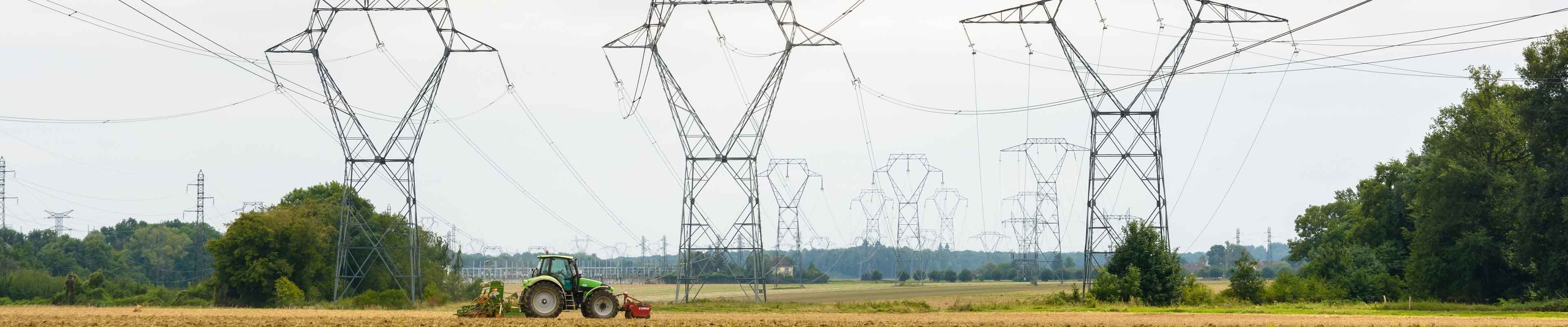 Image of a tractor working beneath power lines.