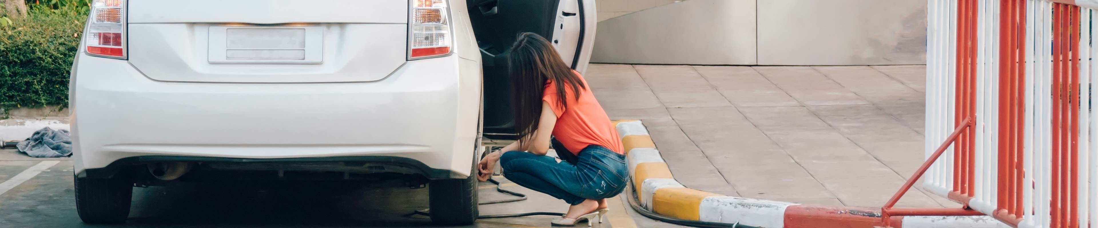 Young woman putting air in her car tires.