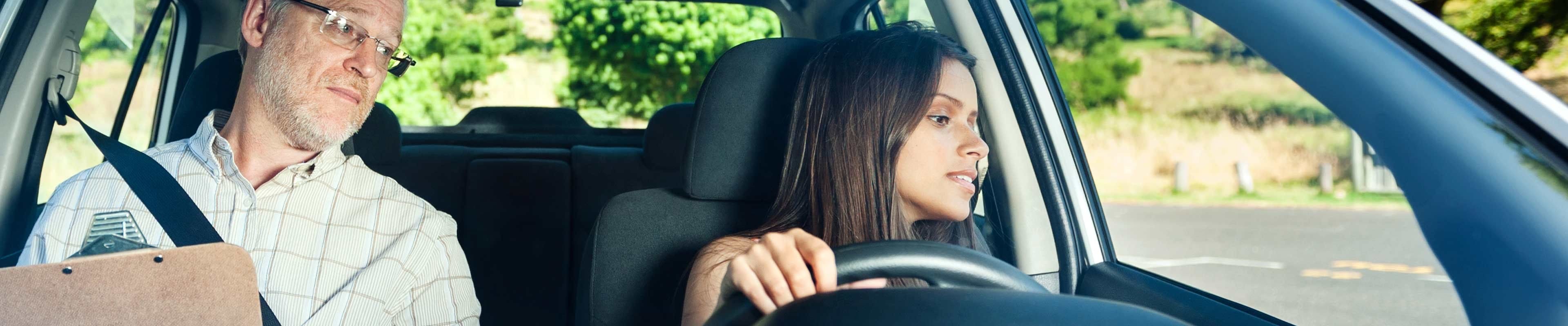 A driving instructor watches as a teen driver reverses the vehicle