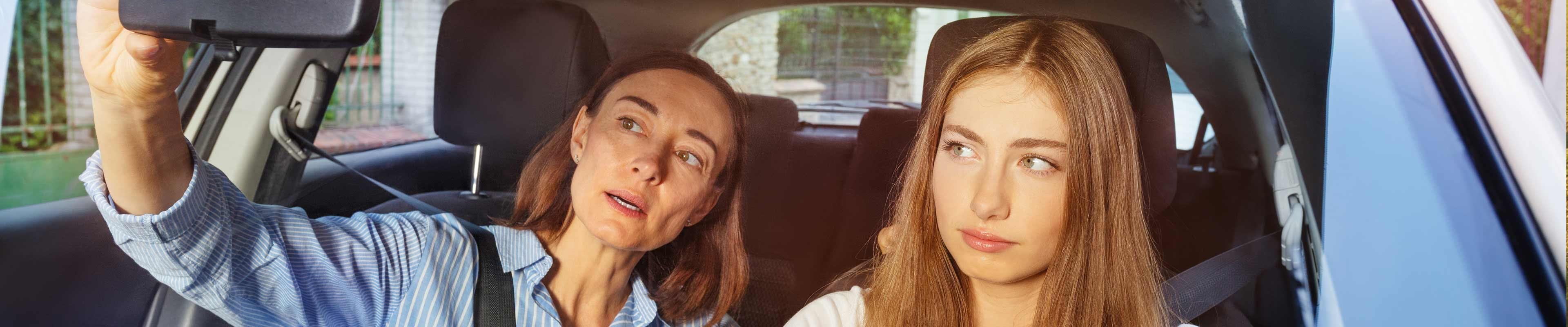 Image of a mother teaching her teen daughter how to drive.