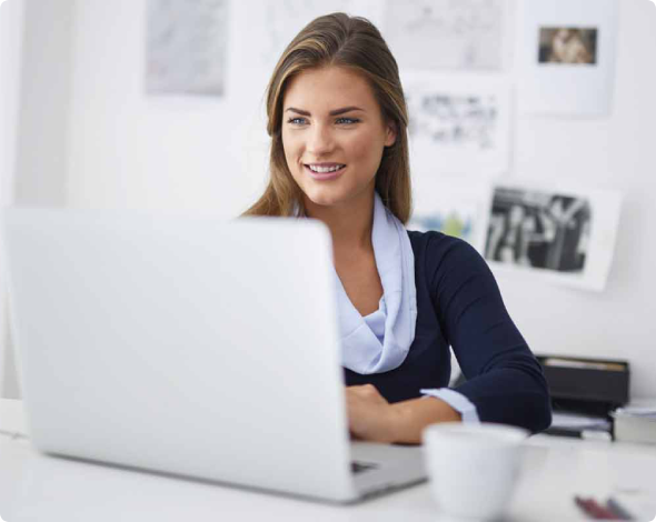 woman sitting at desk, looking at laptop computer and smiling