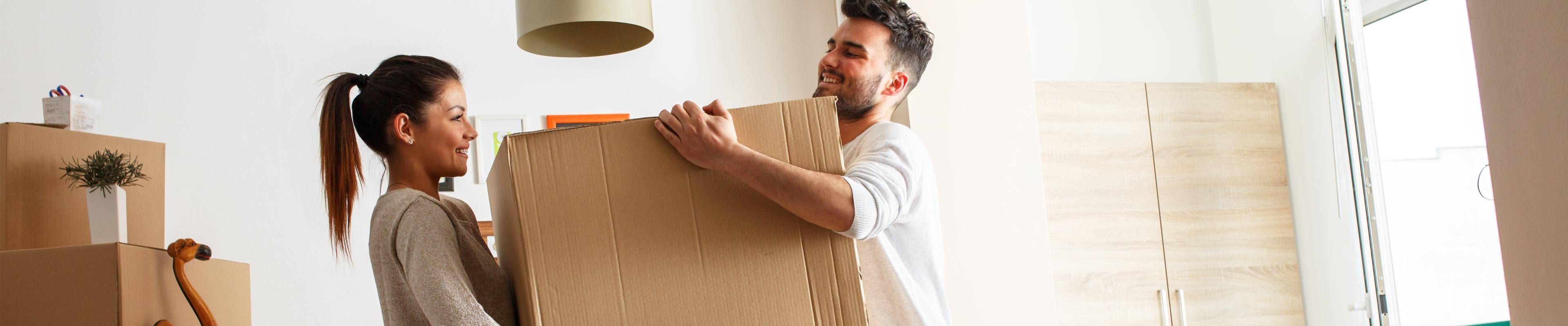 Young couple moving boxes into home