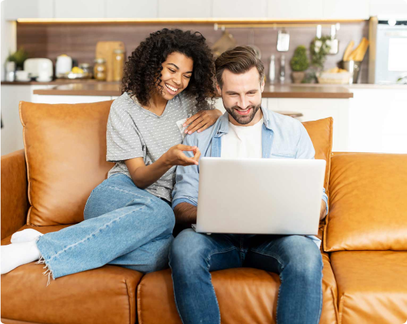 Young couple sitting on couch customizing home insurance online.