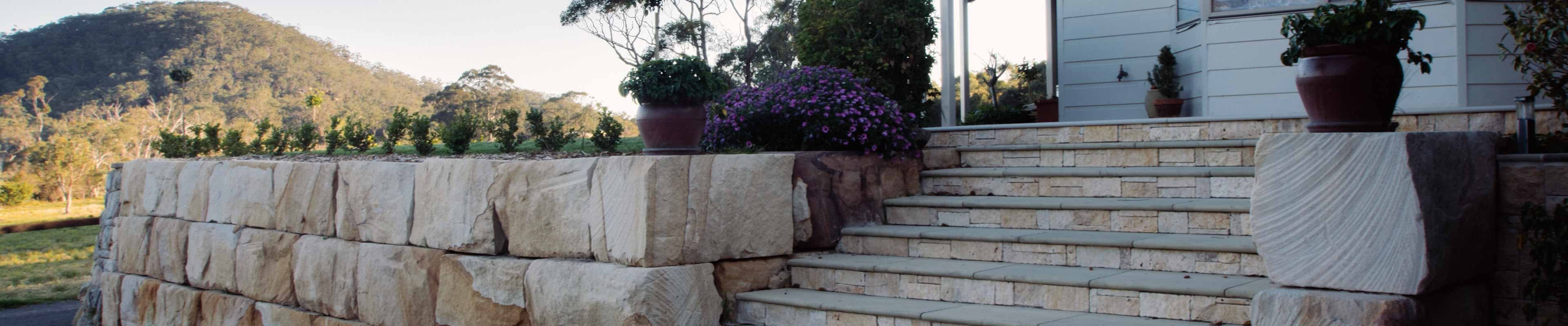 Image of a home entry with stairway and retaining wall, hill off in the distance.
