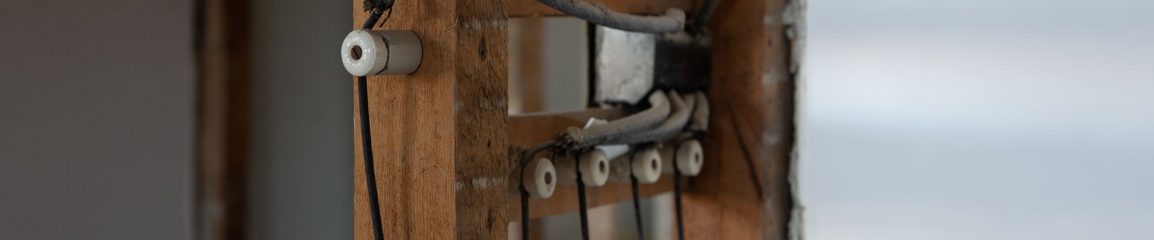 Image of exposed knob and tube wiring within the framing of a home's wall.
