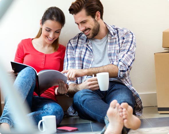 man and woman sitting on floor looking at book