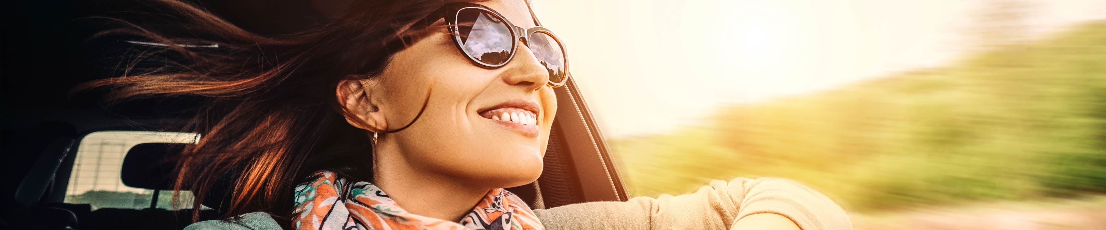 Woman happily driving after getting first car insurance policy 