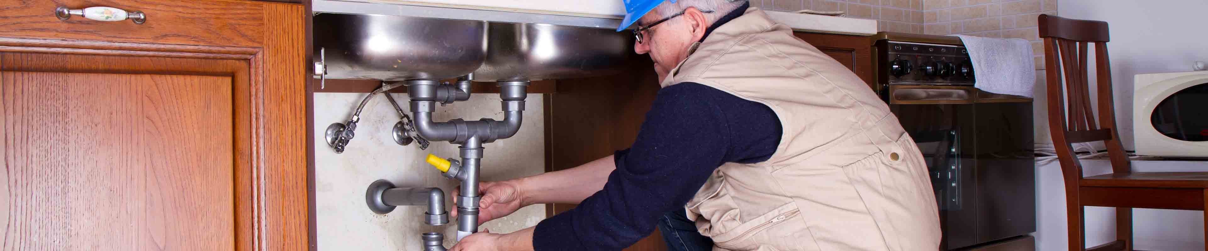 Image of a plumber making a repair to a rental unit's kitchen sink goose neck pipe.