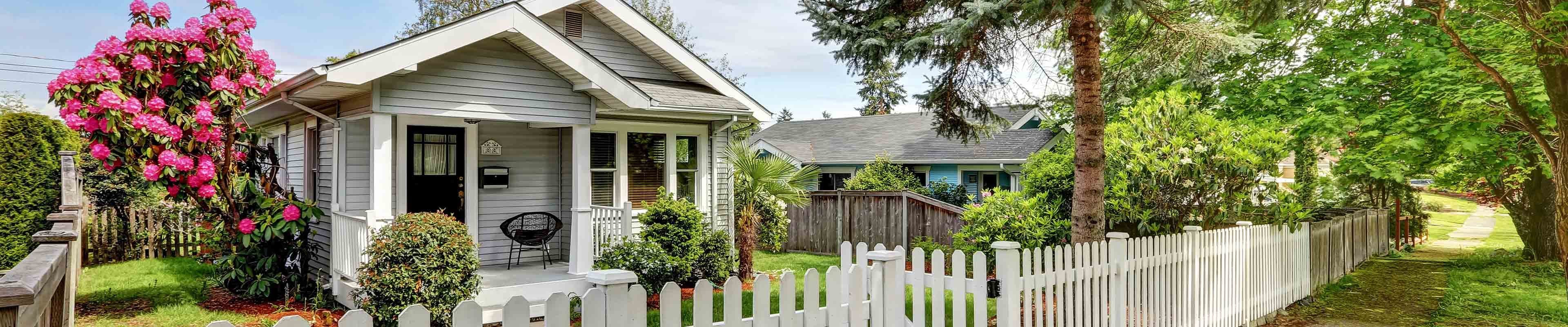 Image of a home with white picket fence and sidewalk. 