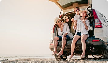 a group of people sitting in a car on a beach