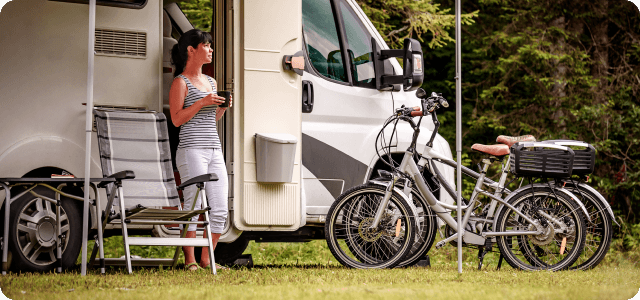 A woman standing next to the door of a parked RV