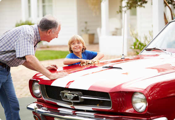 An older man and a young boy cleaning a classic car