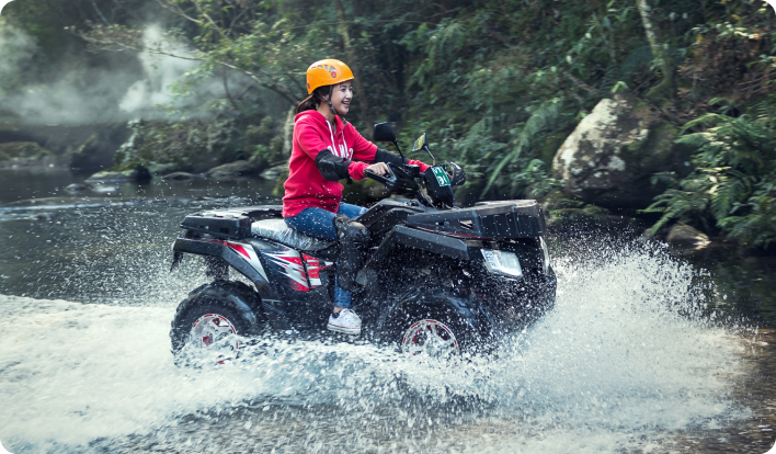 A young girl riding an ATV through water