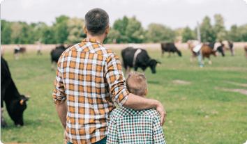 a person and a child looking at cows in a field