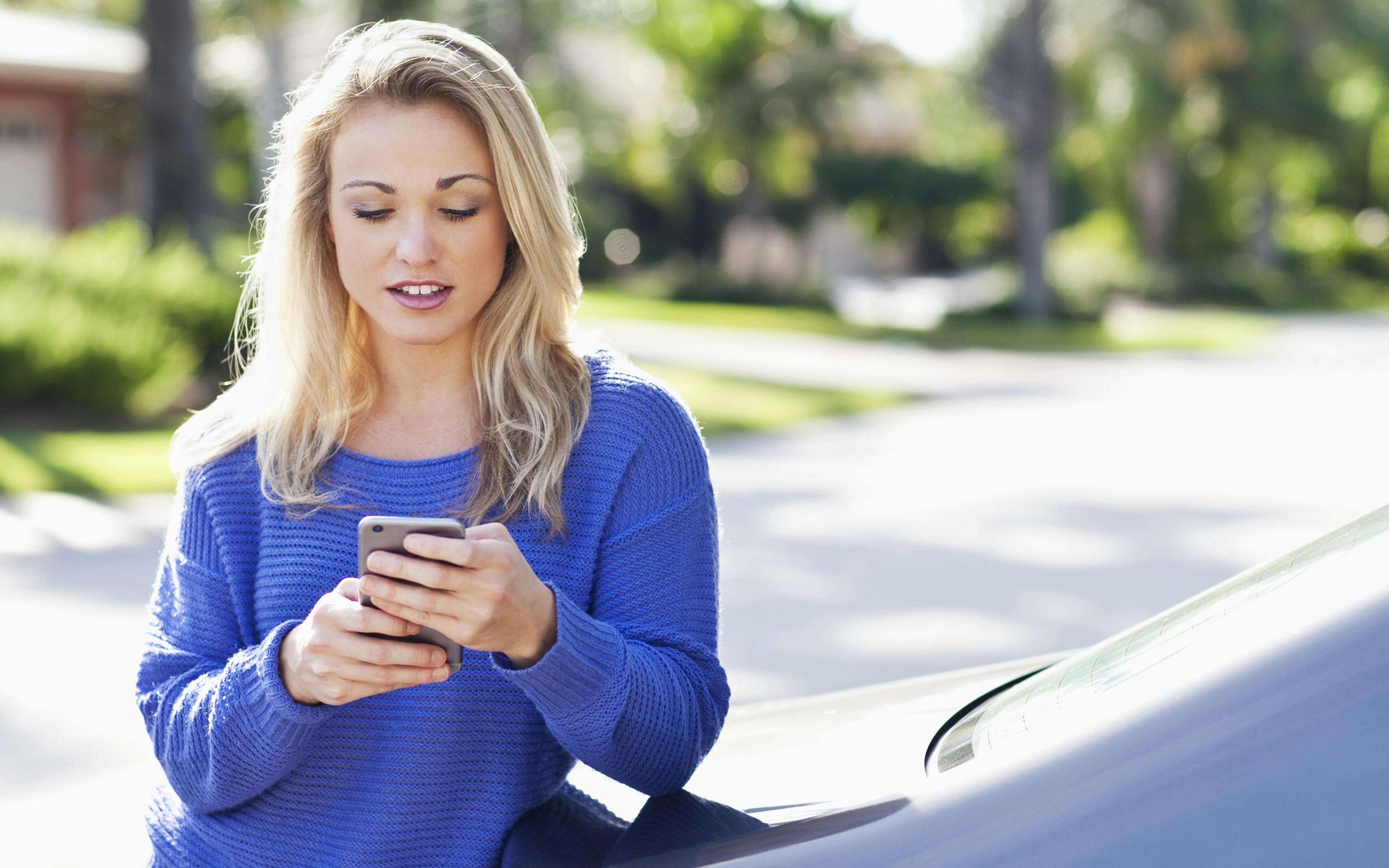 a woman sitting on a curb looking at her phone