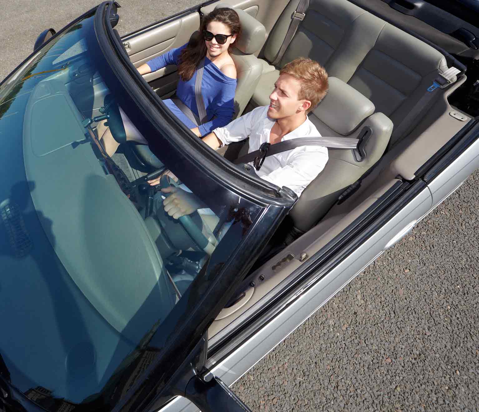 Image of happy couple traveling on highway discussing car insurance rates.
