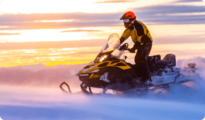 A rider on a snowmobile at sunset